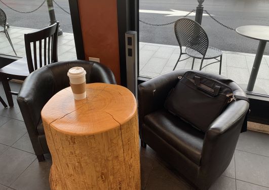 Gray MG Power Plus shown sandwiched between two cushioned chairs at a coffee shop